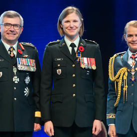 Le lieutenant-colonel Claire Katherine Bramma se tient entre le Vice-chef d'état-major de la Défense, le   Lieutenant-général Paul Wynnyk (à gauche) et Son Excellence la très honorable Julie Payette (à droite).