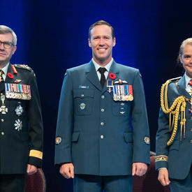 L’adjudant Aaron David Bygrove se tient entre le Vice-chef d'état-major de la Défense, le Lieutenant-général Paul   Wynnyk (à gauche) et Son Excellence la très honorable Julie Payette (à droite).