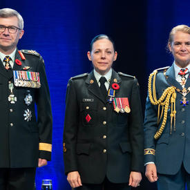 Le sergent Roxane St. Michael se tient entre le Vice-chef d'état-major de la Défense, le Lieutenant-général Paul   Wynnyk (à gauche) et Son Excellence la très honorable Julie Payette (à droite).