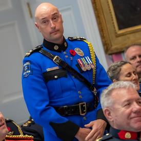 Un récipiendaire de l'Ordre du mérite des corps policiers se tient debout avant de s'approcher de l'avant de la salle pour accepter sa médaille.