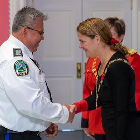 The Governor General shakes hands with a recipient of the Order of Merit of the Police Forces.