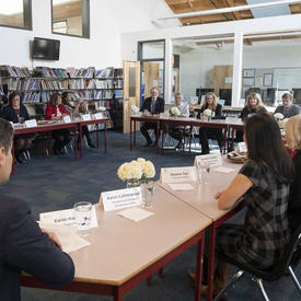  A group of people sit around a table discussing. 