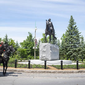 Les chevaux du Carrousel de la GRC se tiennent à côté la statue équestre de la reine Elizabeth II.
