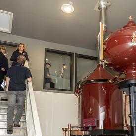 Les propriétaires montrent à la gouverneure générale la salle de l'Alambic à l'intérieur du Verger Poméloi où se fait la distillation.