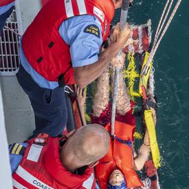 Une photo du NGCC Baie de Plaisance et de son équipage en mer effectuant une démonstration de recherche et sauvetage.