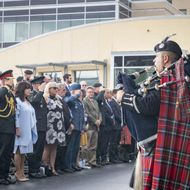 La gouverneure générale, le chef d'état-major de la Défense et les invités présents se tiennent debout et saluent pendant la cérémonie.