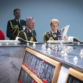 The Governor General and the Chief of the Defence Staff examine the Kandahar Cenotaph and read from an archival book.