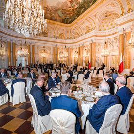 Une photo des chefs d'État assis à des tables à l'intérieur du château royal de Varsovie.