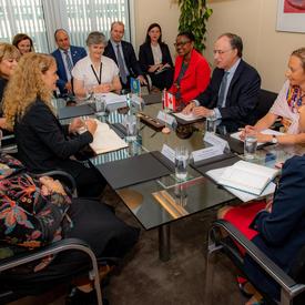 La gouverneure générale assise à une table avec l'ambassadeur du Canada aux Pays-Bas et un groupe d'employés de l’OPCW.