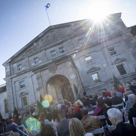 Une photo de l'entrée principale de Rideau Hall, avec des invités assis pour une cérémonie.