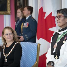 La gouverneure générale observe comment un récipiendaire est investi dans l'Ordre du Canada.
