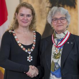 Louise Nadeau se tient à côté de la Gouverneure générale.  Tous deux sourient à la caméra.  Elles portent leur insigne de l'Ordre du Canada.