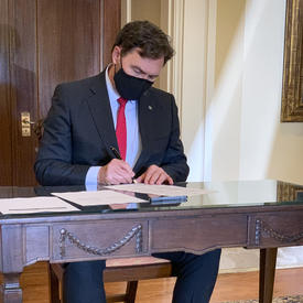 L’administrateur, assis à une table, signe un document.