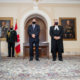 The Administrator is flanked on either side by two people. All five individuals wear masks and maintain physical distancing protocols.