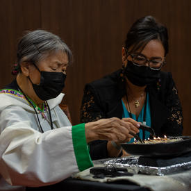 Une Aînée inuite allume le qulliq au Sénat. Une femme est assise à ses côtés. 
