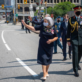La gouverneure générale Mary May Simon salue la foule alors qu’elle se rend en marchant du Sénat au Monument commémoratif de guerre du Canada.
