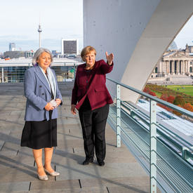 Governor General Mary Simon and Her Excellency Angela Merkel, Chancellor of Germany, are standing on a balcony. The Bundestag is visible behind them.