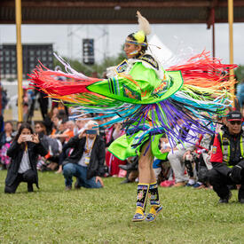 Un artiste habillé de couleurs vives exécute une danse.