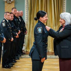 The Governor General is placing a medal on Bravery recipient Constable Annie Arseneau.