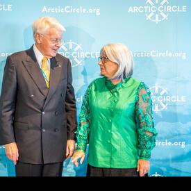 Governor General Mary Simon is standing to the left of Mr. Ólafur Ragnar Grímsson. The light-blue poster behind them reads, “ArcticCicle.org” and “Arctic Circle”.