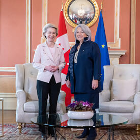 La gouverneure générale Simon se tient à côté de Son Excellence Ursula von der Leyen, la présidente de la Commission européenne. Elles sourient à la caméra. En arrière-plan, on retrouve le drapeau canadien et le drapeau européen.