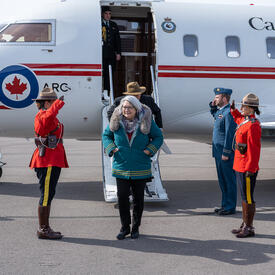 La gouverneure générale Mary Simon marche à l'extérieur. Un avion se trouve derrière elle.