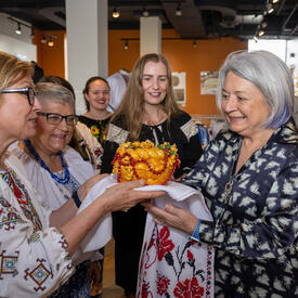 La gouverneure générale Marie Simon reçoit un gâteau d'une dame à lunettes