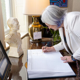 La gouverneure générale Marie Simon signe un livre d'or