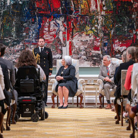 La gouverneure générale Marie Simon est assise sur une chaise pendant la cérémonie