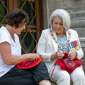 Governor General Marie Simon does crochet with Métis artist Tracey-Mae Chambers.