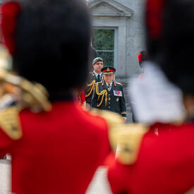 La gouverneure générale Marie Simon est vue entre deux musiciens de la Garde de cérémonie. Elle porte un uniforme de l'armée des Forces armées canadiennes.