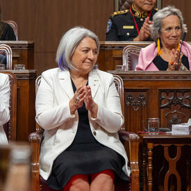 La gouverneure générale Marie Simon est assise et frappe dans ses mains