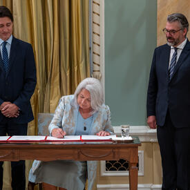 La gouverneure générale Marie Simon signe des documents officiels pendant que le premier ministre Justin Trudeau la regarde