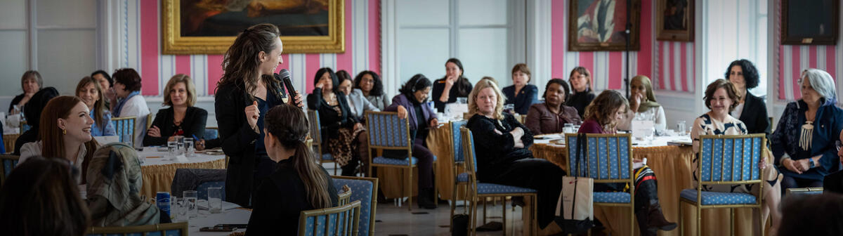 Une femme tient un microphone et parle lors d’un événement dans la salle de la tente à Rideau Hall