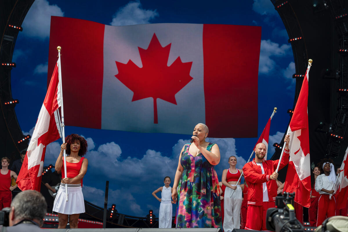 Performers holding Canadian flags during the daytime ceremony.