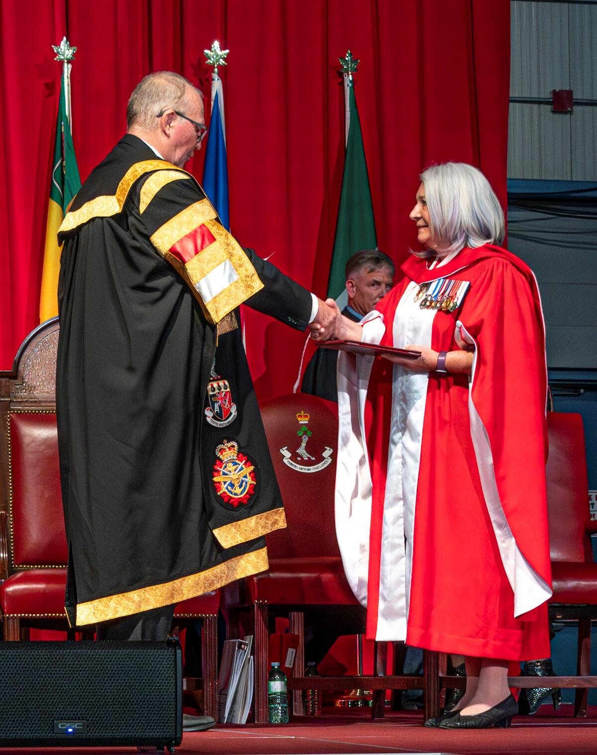 La gouverneure générale serre la main d'un homme alors qu'elle reçoit un diplôme.