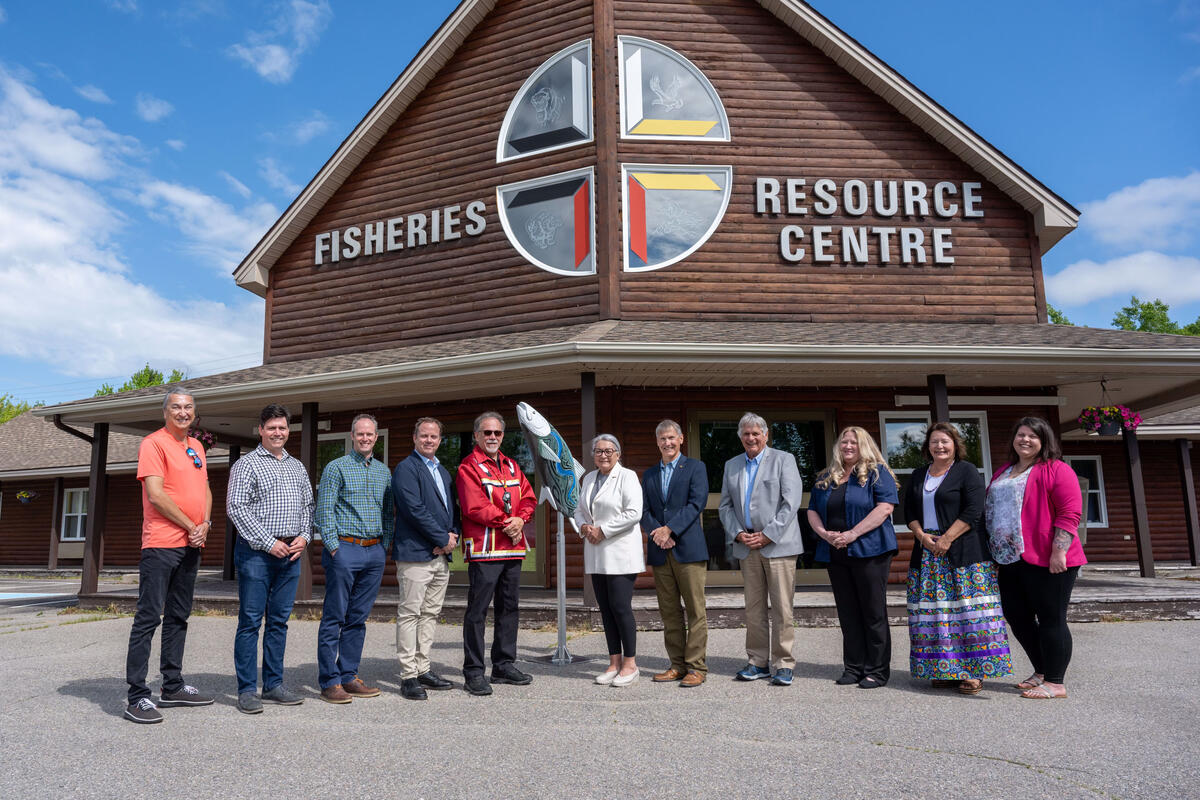Governor General Simon and Mr. Whit Fraser standing outside with a group of people. A large building with the words ‘Fisheries Resource Centre’ on the front is behind them.