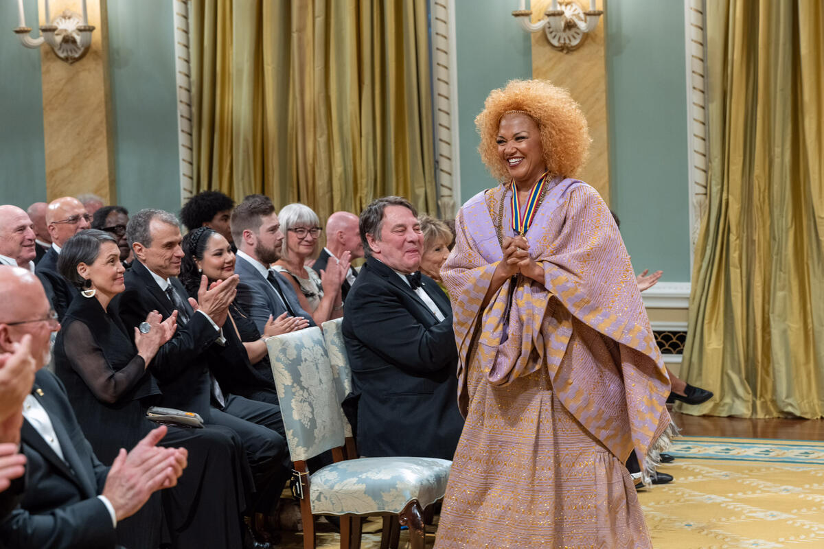 Measha Brueggergosman-Lee stands and smiles while the audience applauds her in the Ballroom at Rideau Hall