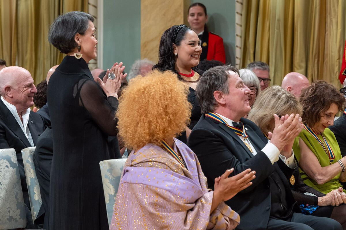 Susan Aglukark, mentor de cette année, et sa protégée Angela Amarualik se lèvent tandis que le public applaudit dans la salle de bal de Rideau Hall.