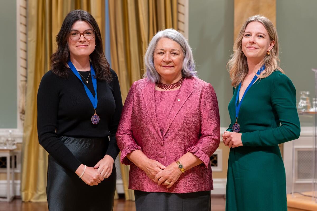 La gouverneure générale Mary Simon se tient entre deux femmes. Elles posent pour une photo.