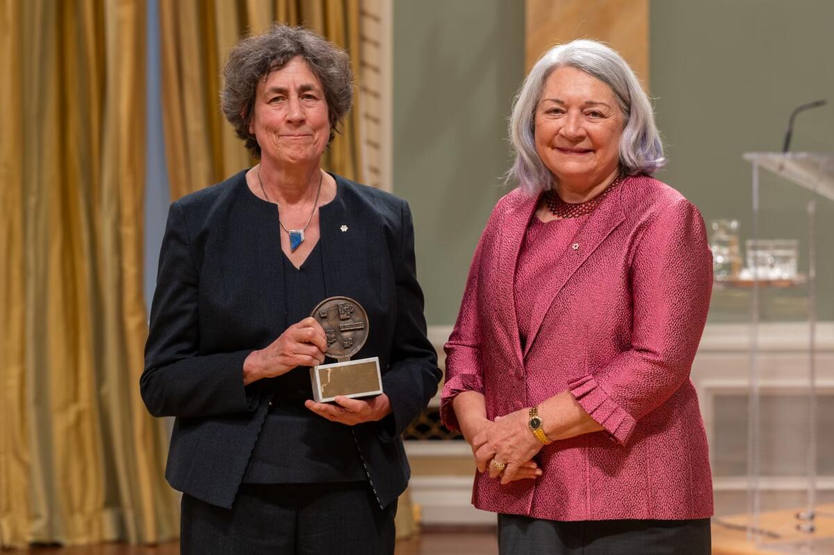 La gouverneure générale Mary Simon se tient à côté d’une femme. La femme tient un trophée. Elles posent pour une photo.