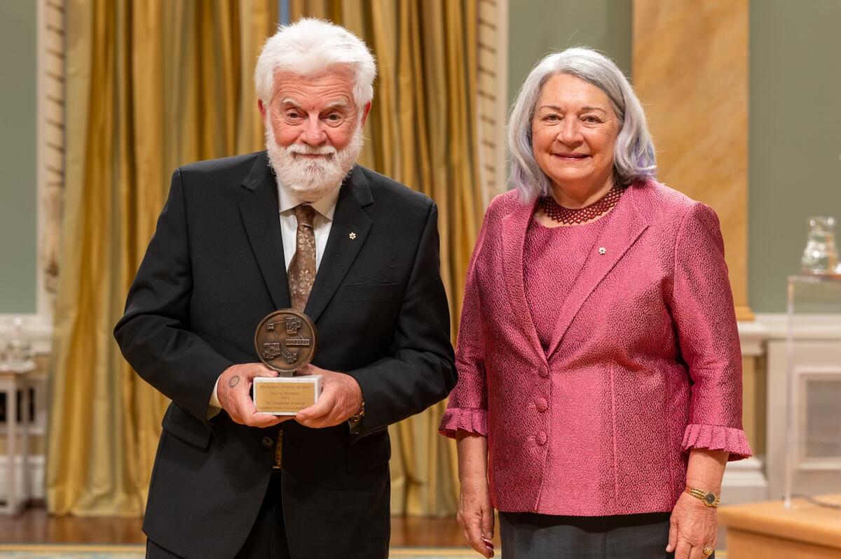La gouverneure générale Mary Simon se tient à côté d’un homme. Celui-ci tient un trophée. Ils posent pour une photo.