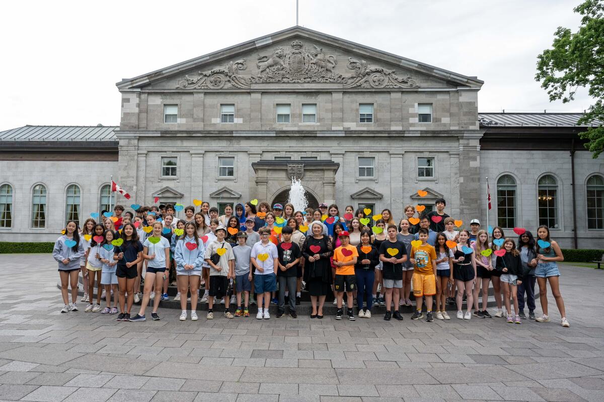 La gouverneure générale Mary Simon se tient avec un grand groupe d'étudiants devant la fontaine de Rideau Hall.