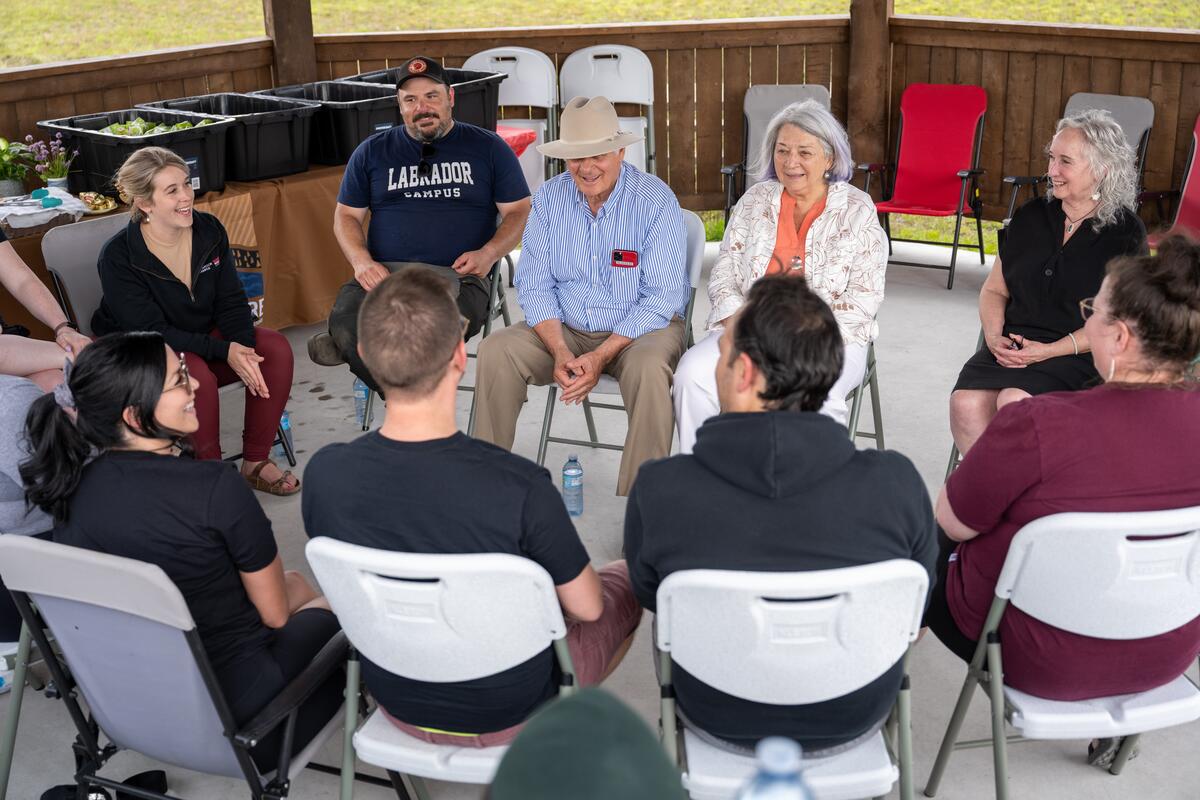 Governor General Mary Simon sits in a circle with staff members. Mr. Whit Fraser sits to her right.