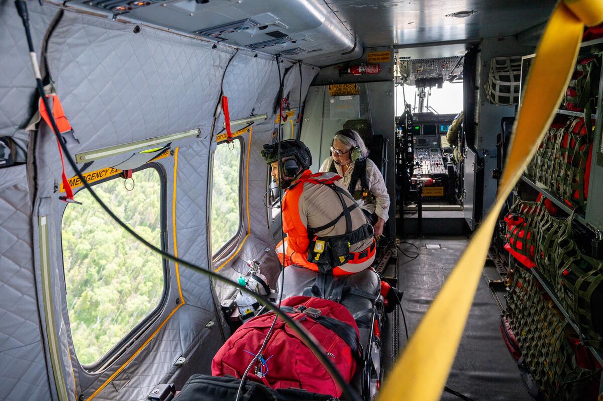 Governor General Mary Simon looks out a helicopter window with a member of the Canadian Armed Forces.