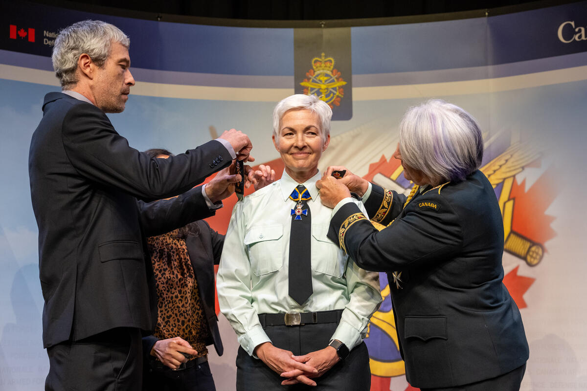 La gouverneure générale Mary Simon attribue de nouvelles épaulettes au général Jennie Carignan. Un homme fait de même à gauche de la photo.