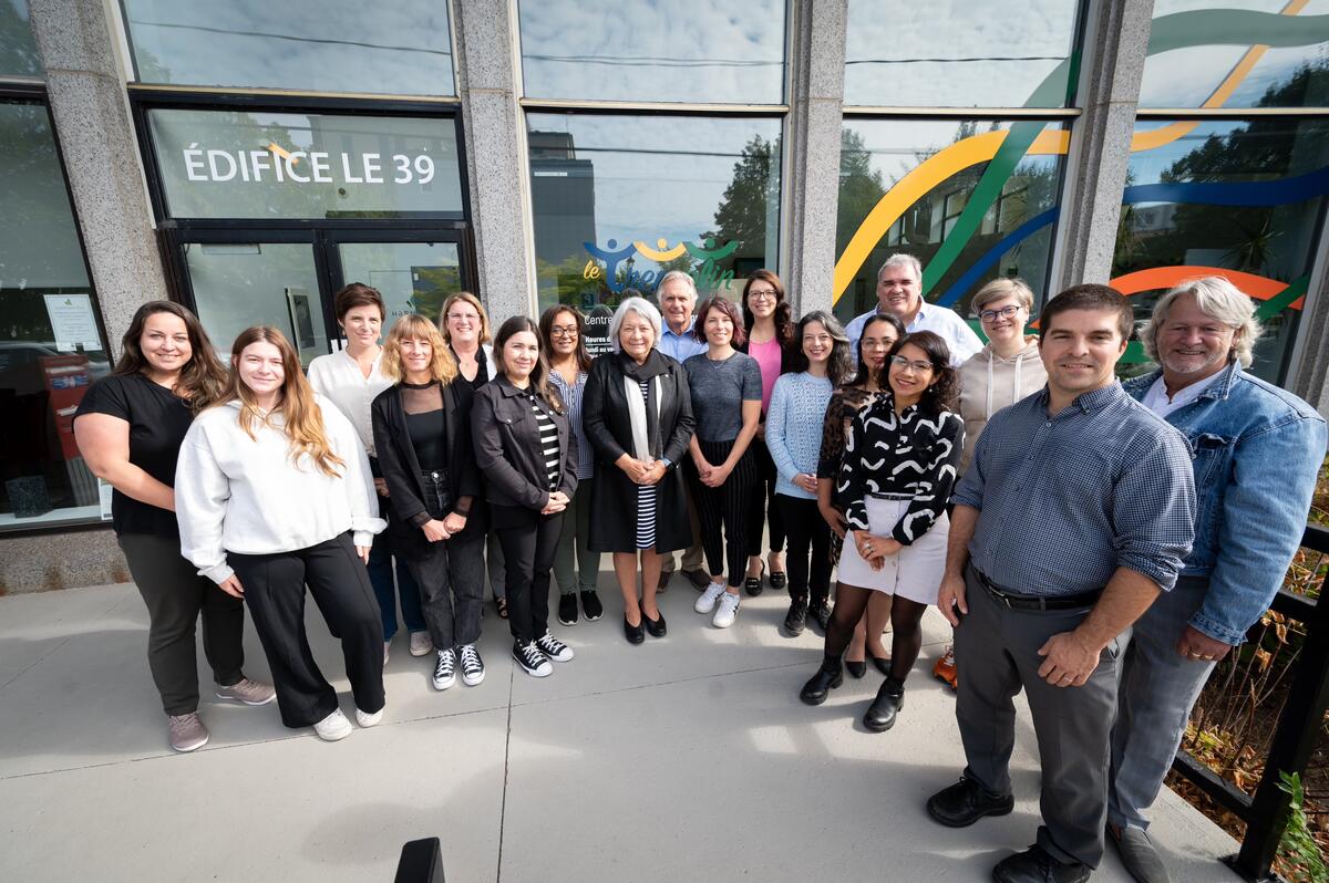 La gouverneure générale Simon pose pour une photo de groupe. Ils se trouvent à l'extérieur d'un immeuble de bureaux.