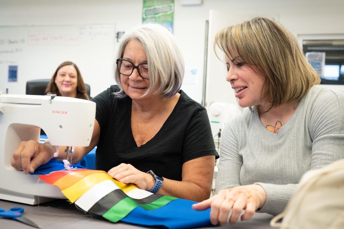 La gouverneure générale Mary Simon et une autre personne sont assises une à côté de l'autre et font de la couture.