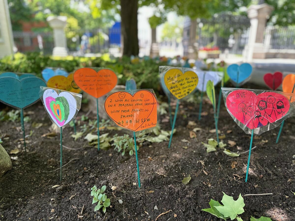 Cardboard hearts with messages, taped to green sticks, all placed in the grass on the grounds of Rideau Hall.