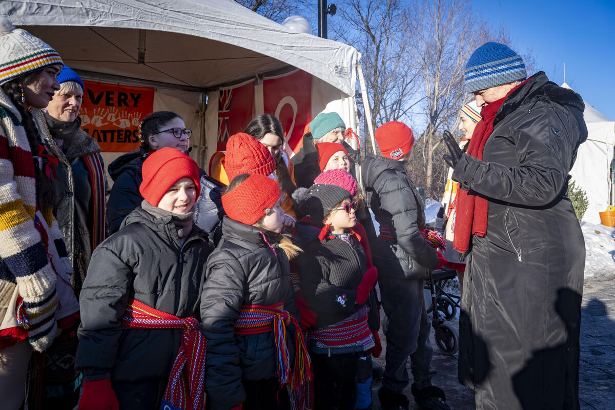  La gouverneure générale Mary Simon salue un groupe d'enfants. Tout le monde est habillé chaudement pour le temps hivernal.